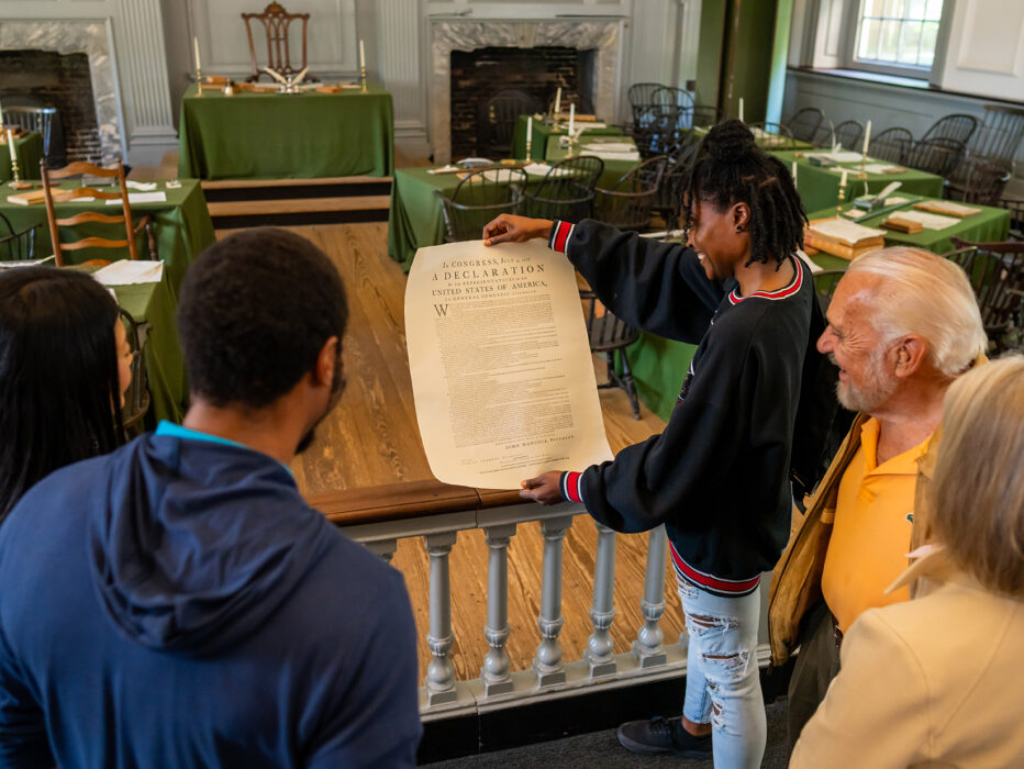 Cinco personas exploran el interior del Independence Hall y contemplan una réplica de la Declaración de Independencia.