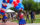 People walking in a parade line holding colorful balloons during Red, White & Blue To-Do. A woman waves at the camera