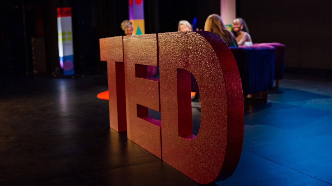 A closeup shot of large red letters that read "TED" on a black stage.