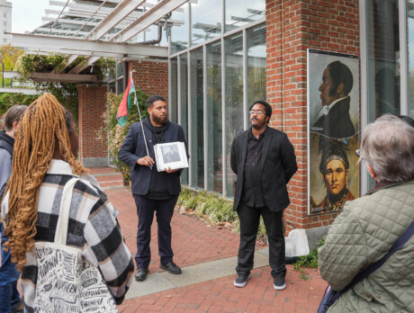 Tour tour guides wearing all black lead a group in the The Original Black History Tour in Philadelphia. The group stops in front of the Liberty Bell Center.