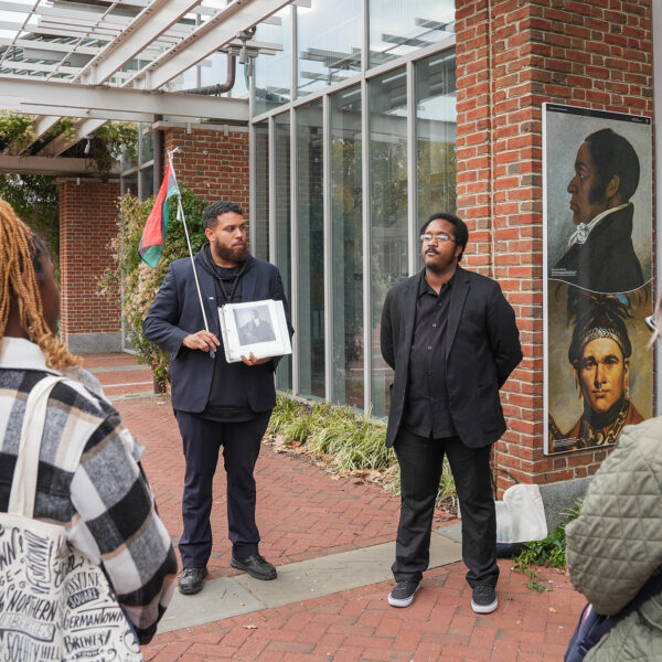 Tour tour guides wearing all black lead a group in the The Original Black History Tour in Philadelphia. The group stops in front of the Liberty Bell Center.