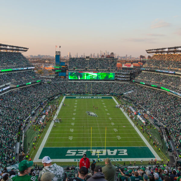 A packed Lincoln Financial Field during a Philadelphia Eagles game, with fans filling the stands around the football field and the Philadelphia skyline visible in the distance.