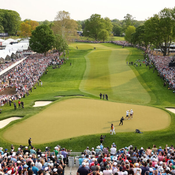 Crowds of spectators watch a professional golfer on the green and fairway during the PGA Championship.