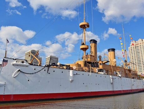 Photo of the USS Cruiser Olympia floating on the Delaware River, Philly skyline in the background