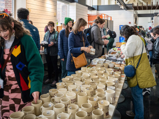 Los compradores examinan tazas de color beige y otros productos artesanales en un mercado emergente de Art Star.