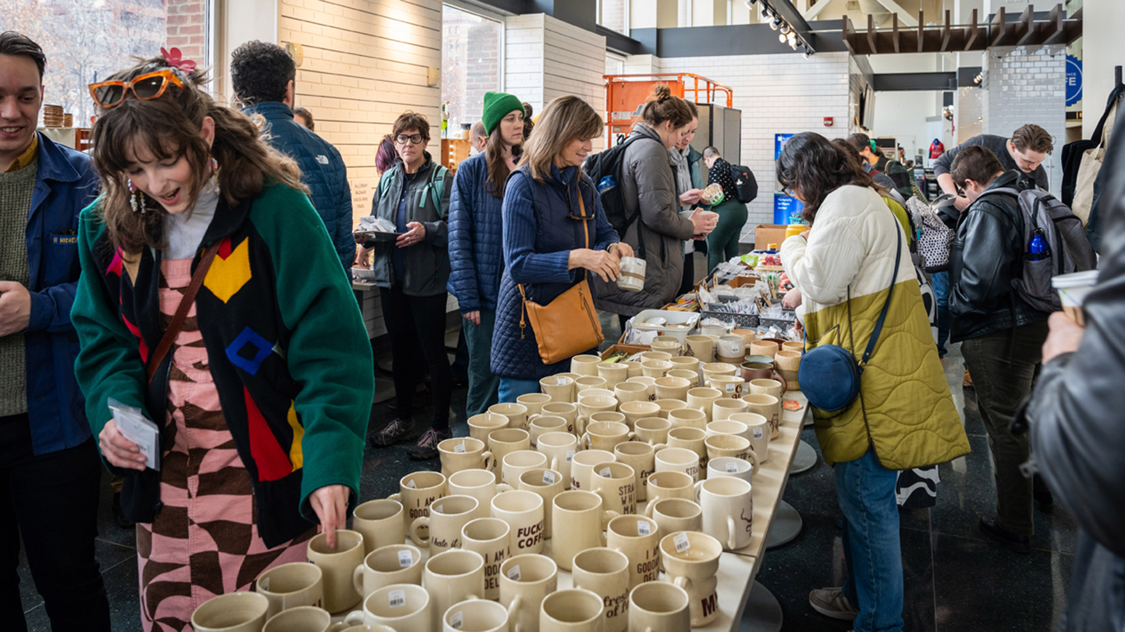 Shoppers bekijken beige mokken en andere handgemaakte producten op een pop-upmarkt van Art Star.