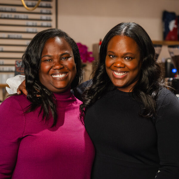 Sisters Sharaine and Sharla Brown pose for a photo and smile at the camera together at their coffee shop Arterial Coffee.
