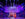 Performers on stage in colorful, Renaissance-inspired costumes sing and dance under vibrant purple and blue stage lighting.