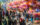 People walk through the exhibit hall at the Philadelphia Flower Show. Pink and orange flower arrangements hang from the ceiling.