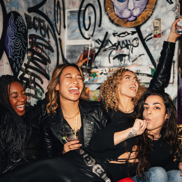 Un groupe de femmes crient et applaudissent devant le mur de style punk de Tattooed Mom.