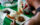 A diner sits at a green table and digs into a meal of pulled beef, a white rice, black beans and fried plantains.