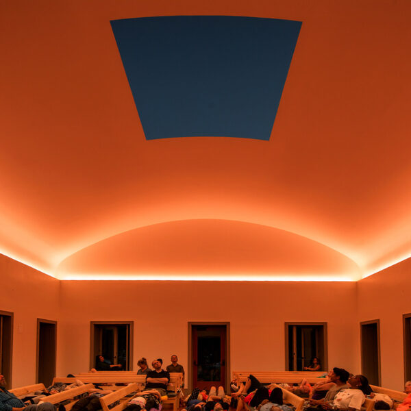 Los visitantes del Chestnut Hill Skyspace contemplan la puesta de sol a través de un agujero en el tejado mientras se proyecta luz en el techo a su alrededor