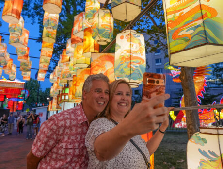Two people pose for a selfie while walking through a walkway illuminated by Chinese lanterns at the Chinese Lantern Festival in Philadelphia.