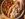 A hand with silver painted nails reaches for half a a cheesesteak on a round plate with crispy French fries and pickle slices. The Wit or Witowski Kielbasa Cheesesteak includes chipped kielbasa with onions and melted American cheese on a long roll.