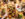 A variety of Polish-inspired dishes, including Sunday chicken, Kielbasa and cream cheese with capers is spread across a wooden table. Several hands reach for the food with utensils.