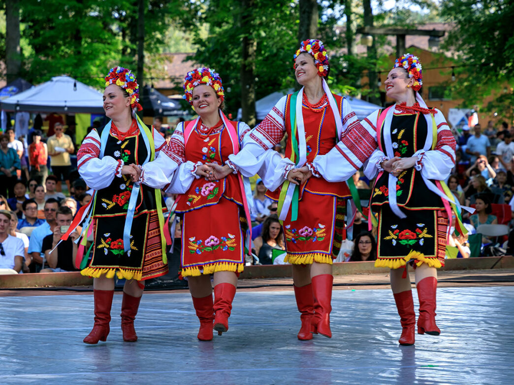 Dancers in red and black outfits link arms and perform on stage during the Ukrainian Folk Festival in Philadelphia.