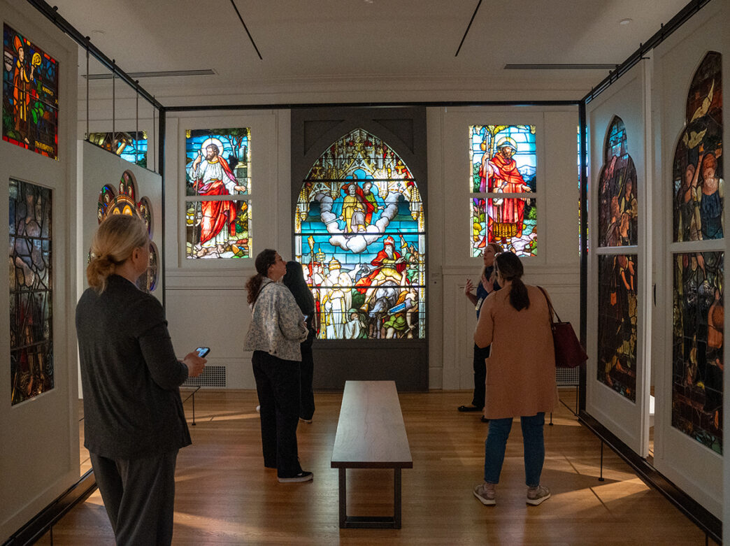 Visitors admire colorful stained glass window panels on display inside the Frances M. Maguire Art Museum at Saint Joseph's University.