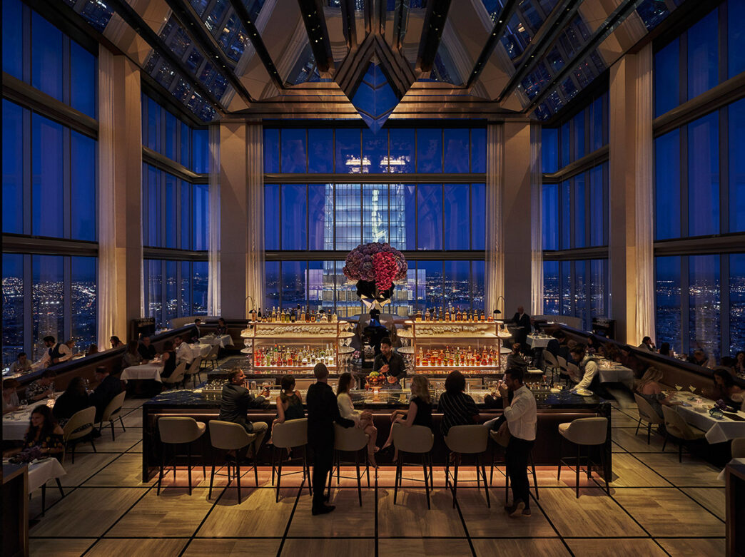 Las ventanas de piso a techo ofrecen unas vistas nocturnas deslumbrantes de la ciudad a los huéspedes que disfrutan de una copa y una cena en el elegante bar del SkyHigh.