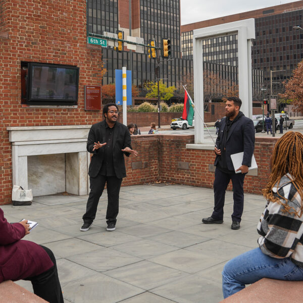 A tour guide from The Black Journey speaks to a group of seated tourgoers at The President's House in Philadelphia