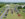 Mustang and Ford cars are parked in a grass field while people walk around and look at the cars.