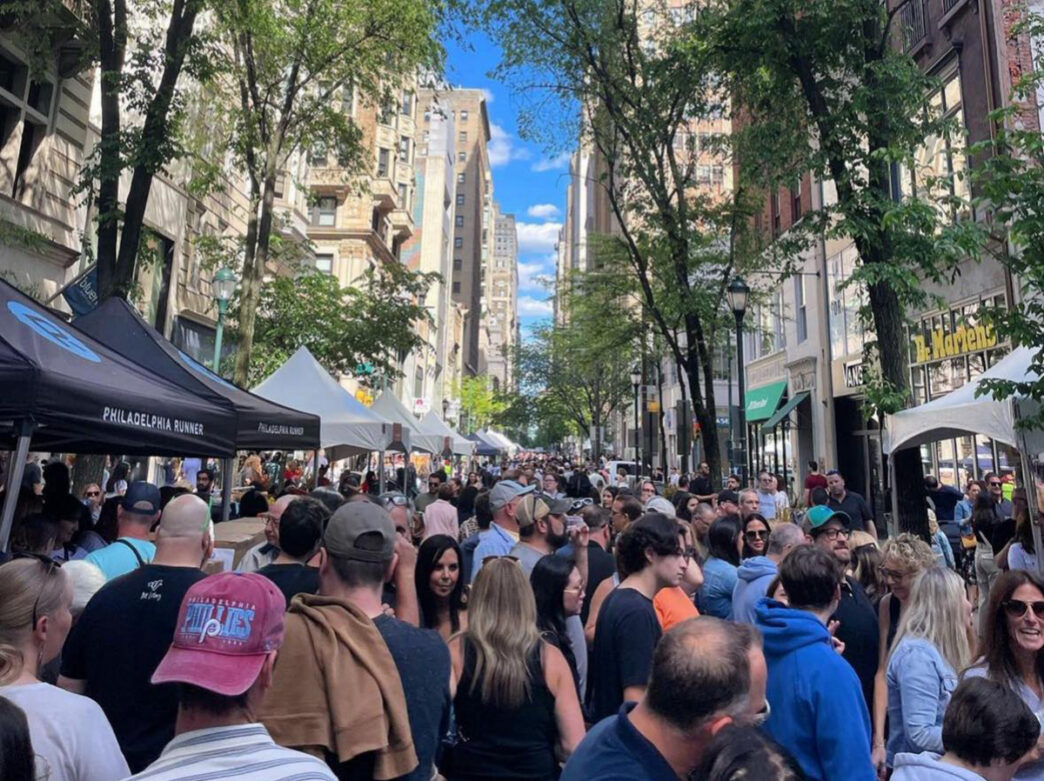 Crowds of people walk down the 1700 block of Walnut Street during Rittenhouse Row Spring Festival. The street is lined with vendor tents and stores.