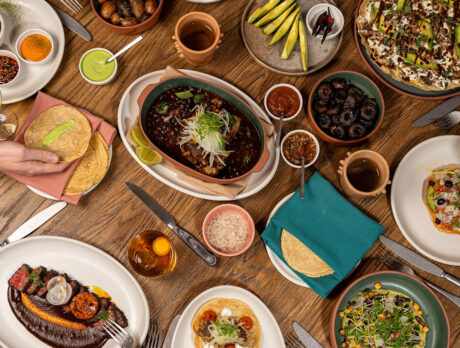A variety of Mexican dishes, including tortillas, a tuna tostada and carne asada, sit on a wooden table at Amá