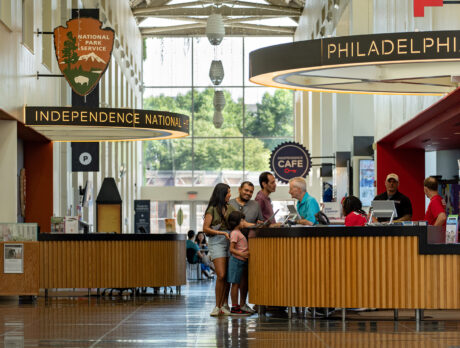 People stand at an information desk and speak to a staff member in Philadelphia Independence Visitor Center.