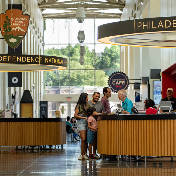 People stand at an information desk and speak to a staff member in Philadelphia Independence Visitor Center.