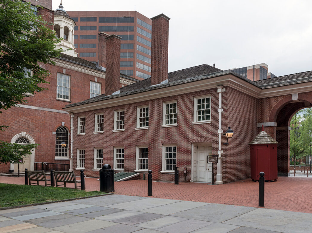 A view of the brick West Wing of Independence Hall, featuring arched doorways and classic colonial architecture.
