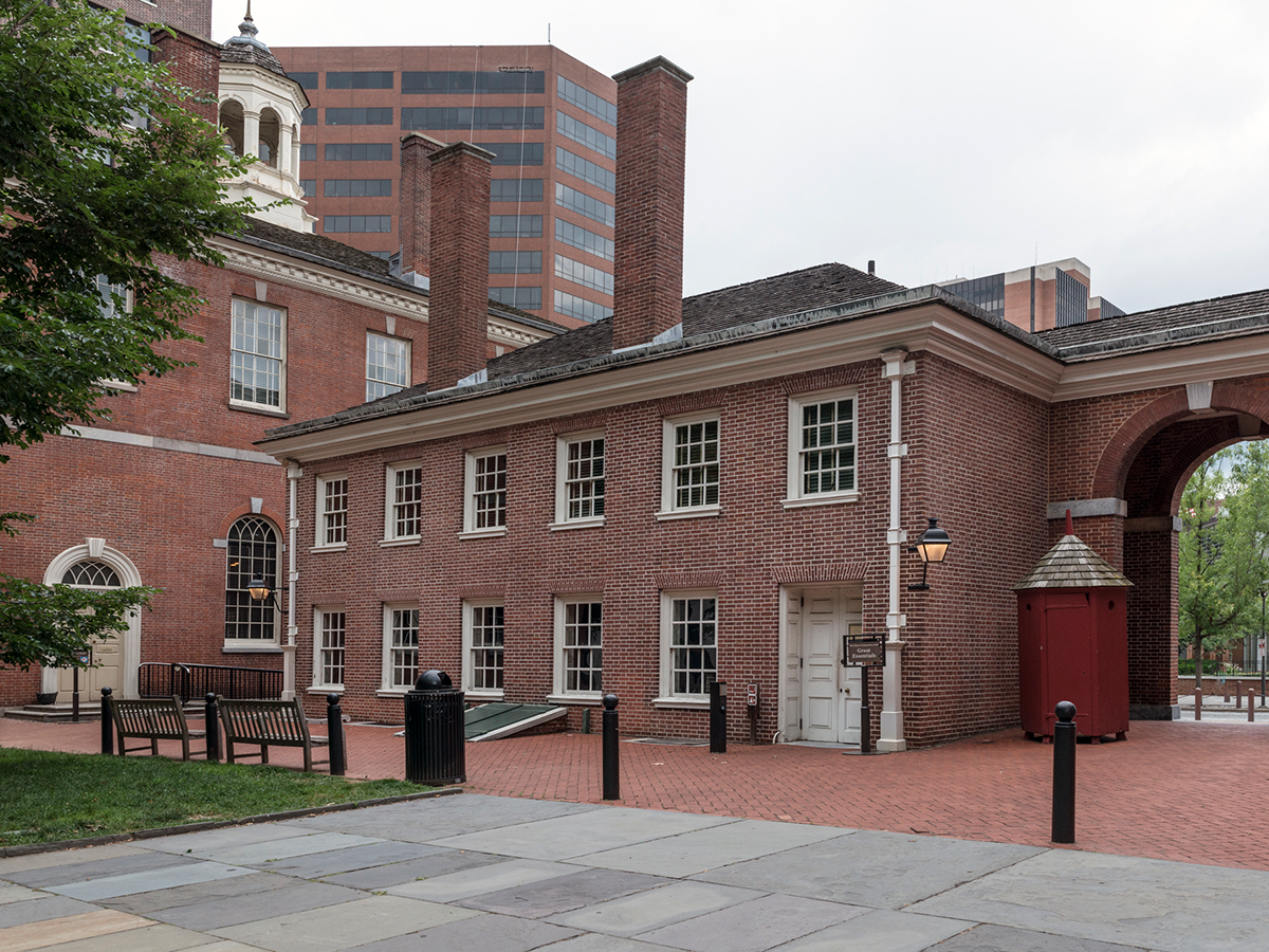 A view of the brick West Wing of Independence Hall, featuring arched doorways and classic colonial architecture.