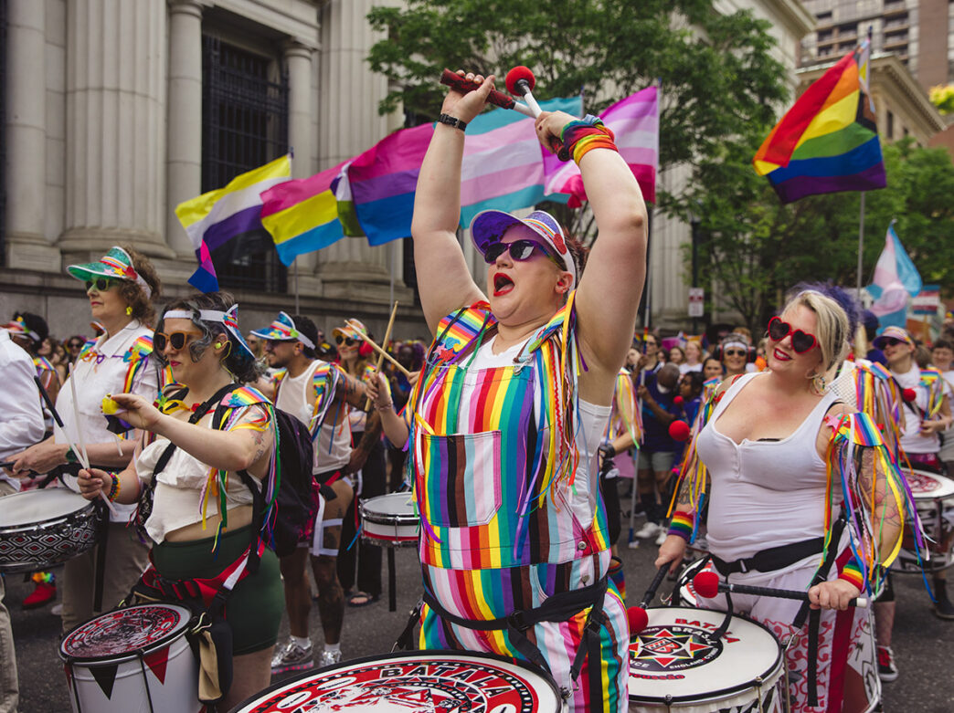 Les membres de la ligne de tambour énergique et drapée d'arc-en-ciel mènent la marche des fiertés Philly dans les rues de la ville.