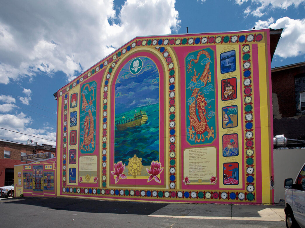 The exterior of the Chua Bo De Buddhist Temple set against a blue sky with white clouds. The building is decorated with a colorful mural.