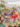 People eat at a table full of food and drinks, women sit on a colorful hammock and a crowd of people walk along the waterfront at Spruce Street Harbor Park