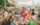 People eat at a table full of food and drinks, women sit on a colorful hammock and a crowd of people walk along the waterfront at Spruce Street Harbor Park