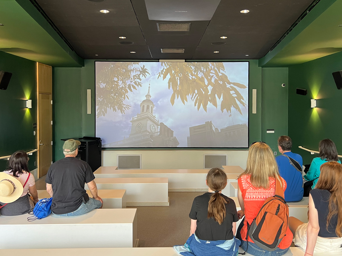 Visitors sit in a small theater watching a short film about Philadelphia at the Independence Visitor Center.