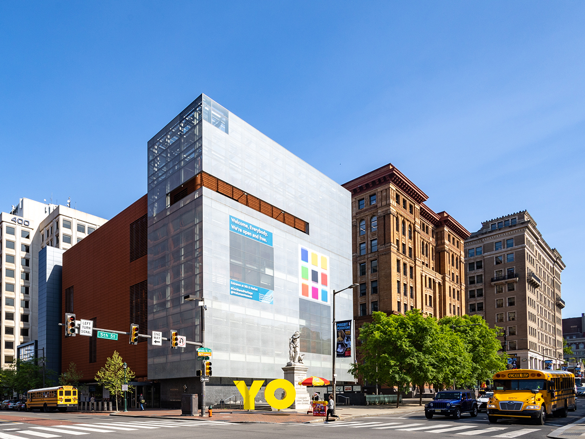 Een knalgele sculptuur van de letters Y en O staan buiten een glazen gebouw, de Weitzman National Museum of American Jewish History.