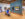 Two people sit on a bench and look at two paintings hung on a gallery wall at the Brandywine Museum of Art. Other people walk around and look at the artwork.