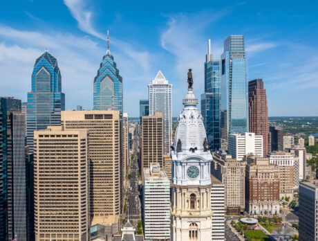 Philadelphia's Center City skyline, featuring the William Penn statue atop City Hall surrounded by modern glass skyscrapers beneath a bright blue sky.