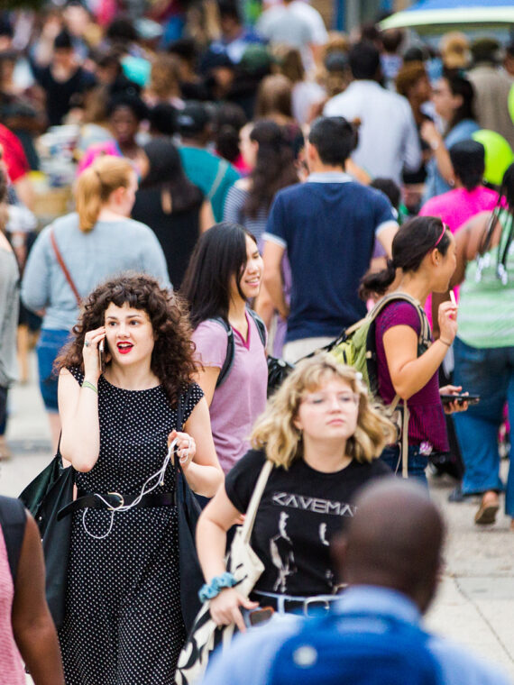 A bustling crowd fills Baltimore Avenue during the Dollar Stroll. People socialize, walk and stop for drinks.