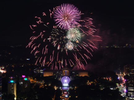 A glowing fireworks display explodes over the Philadelphia Museum of Art and Benjamin Franklin Parkway in a night sky.