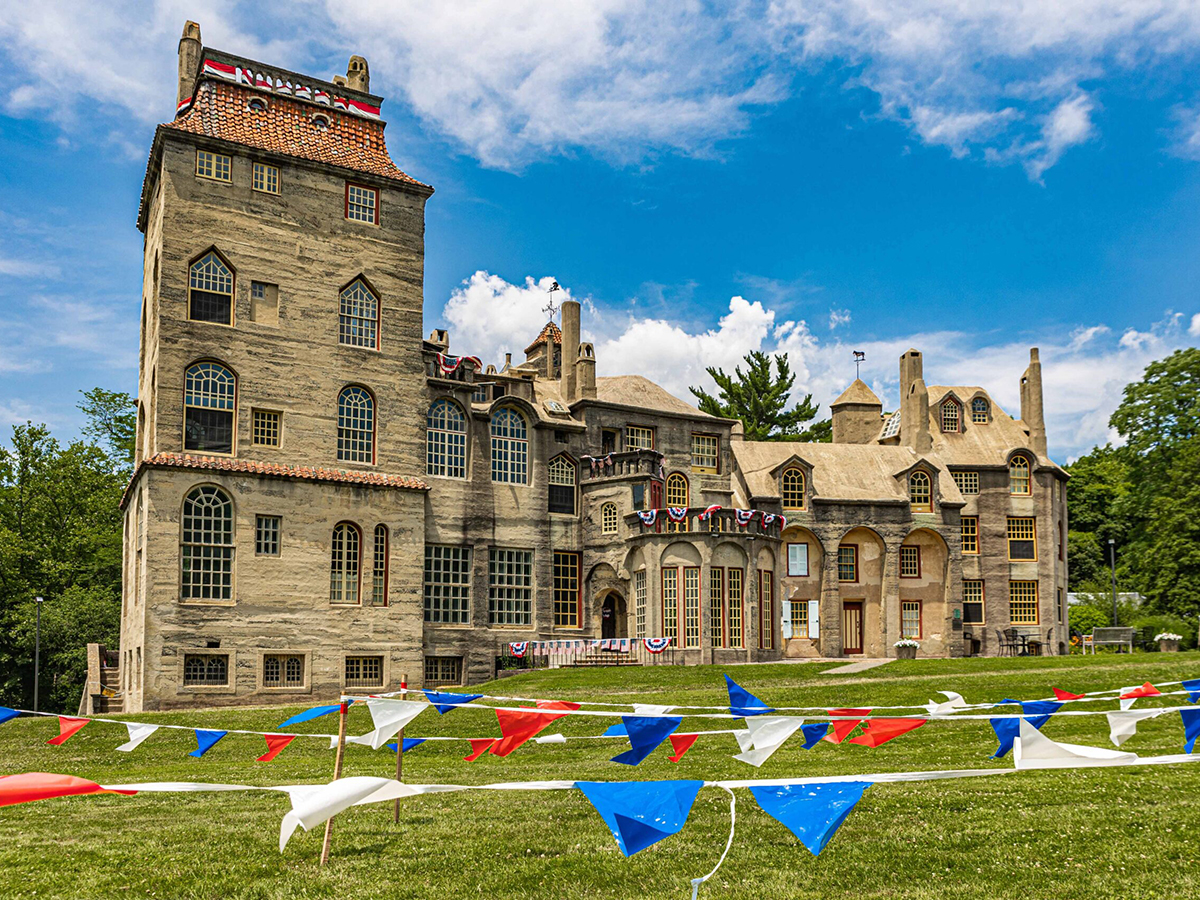 A large tan castle is decorated with red, white and blue bunting for the Fourth of July, with patriotic pennant flags in the foreground.