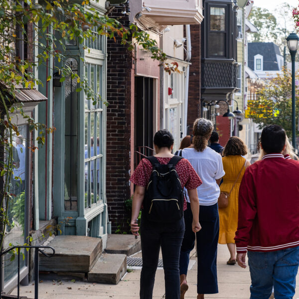 Visitors stroll down a charming street lined with historic storefronts and row homes in Philadelphia's Germantown neighborhood.