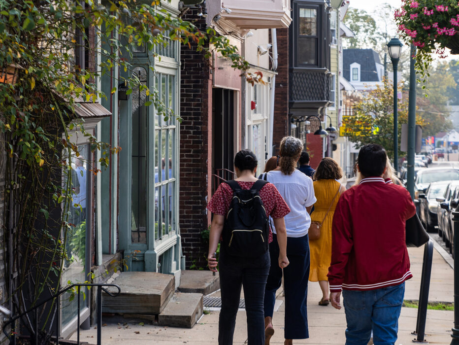 Visitors stroll down a charming street lined with historic storefronts and row homes in Philadelphia's Germantown neighborhood.
