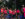 A group of Juneteenth Parade participants dressed in matching bright pink shirts smile and wave as they walk along the parade route.