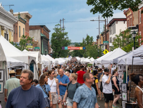 A large crowd shops at white vendor tents lining Main Street at the Manayunk Arts Festival.