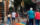 A group of people cross a colorful rainbow crosswalk in Philly's Midtown Village neighborhood, with brick buildings and leafy trees in the background.
