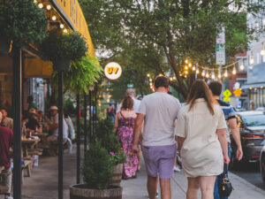 Mensen lopen weg van de camera op een levendige stoep in de wijk Northern Liberties in Philadelphia, langs terrasjes.