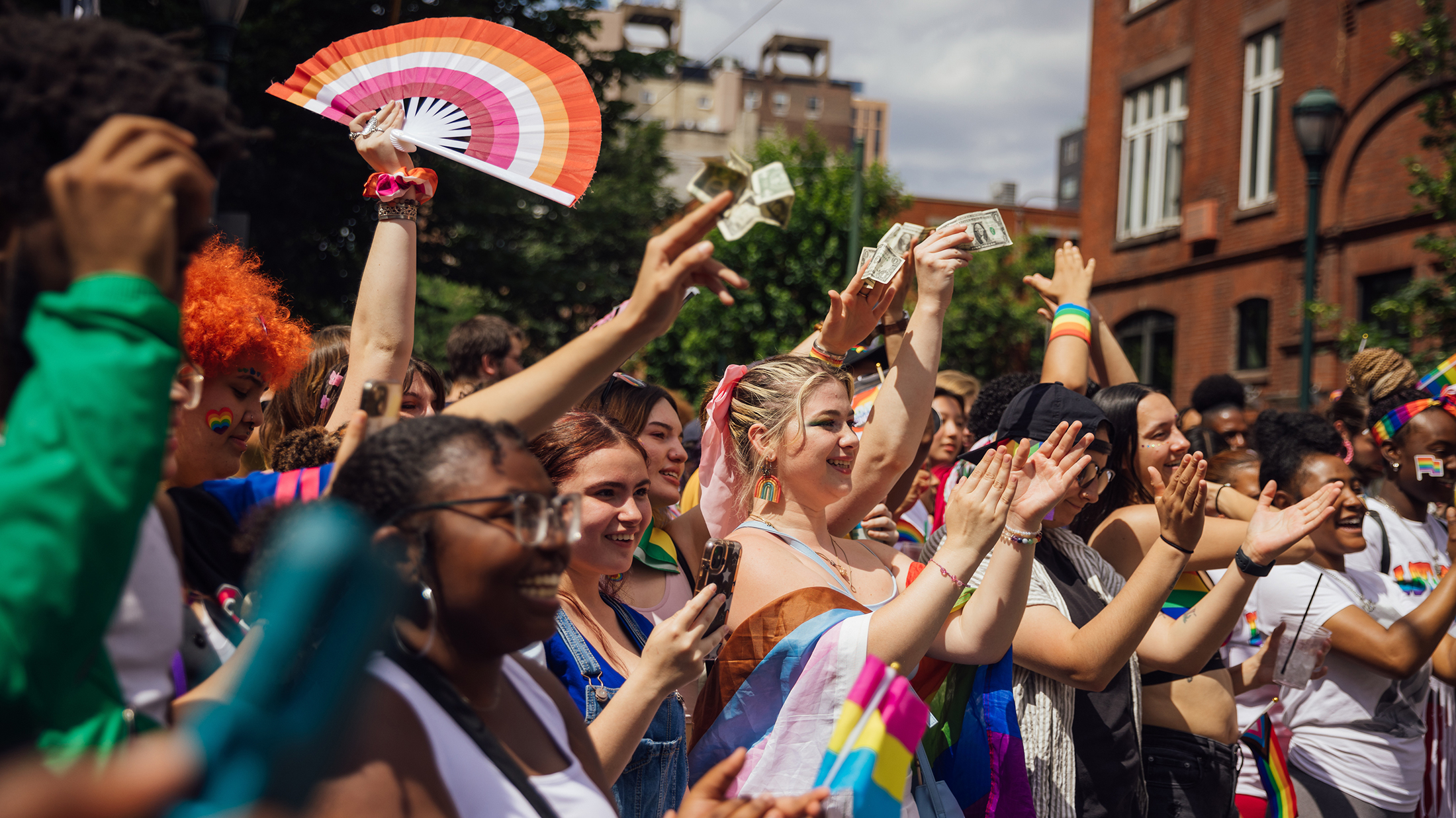 People wearing rainbow outfits and accessories clap and cheer during the Pride March and Festival in Philadelphia.