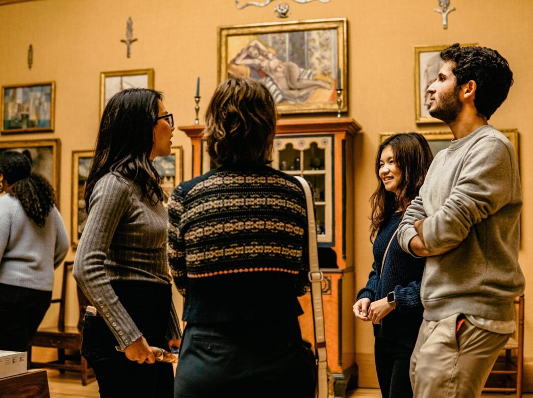 A group of visitors stand in conversation surrounded by artwork at the Barnes Foundation's galleries.