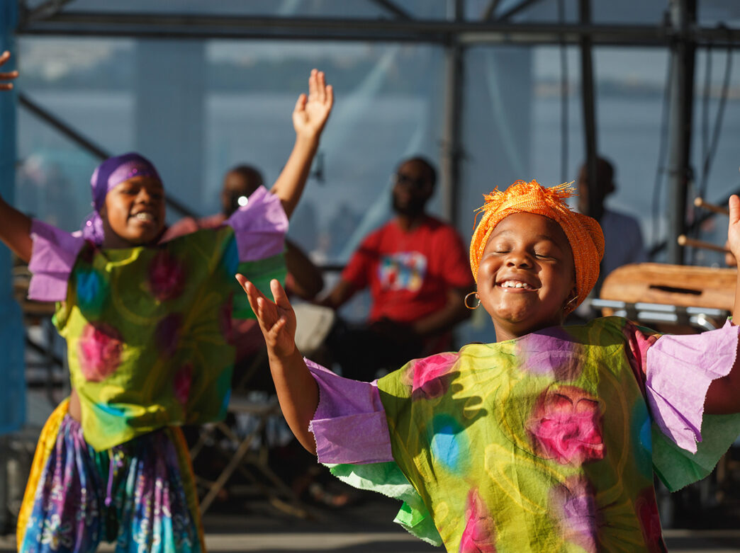 Two young girls in bright, colorful garments perform a joyful dance at the Islamic Heritage Festival.